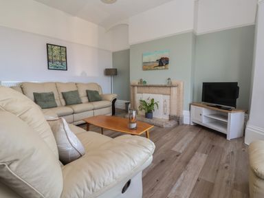 A living room with beige sofas a wooden coffee table a fireplace and a television at 46 The Promenade in Withernsea