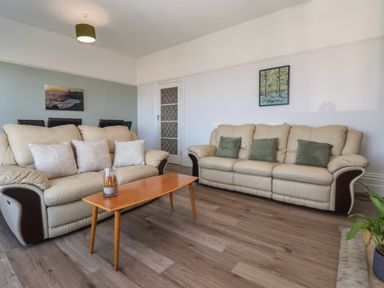 A living room with two beige sofas a wooden coffee table and paintings on the wall at 46 The Promenade in Withernsea