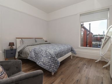 A bedroom with a bed a bedside table with lamp an armchair and large window at 46 The Promenade in Withernsea