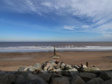 A rocky beach with a wooden groyne extending into the sea at 46 The Promenade in Withernsea