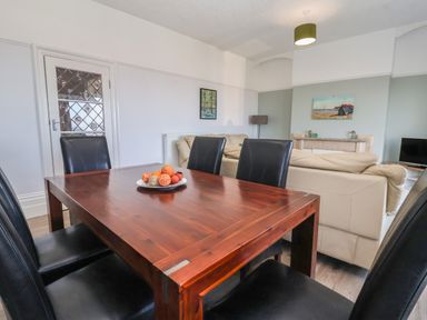 A dining table with black chairs and a beige sofa in a living room at 46 The Promenade in Withernsea