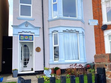Front of a house with a stained glass over the door plants in pots and a garden at 46 The Promenade in Withernsea