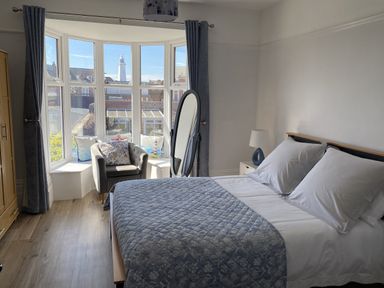 A bedroom with a bed and a chair near windows at 46 The Promenade in Withernsea