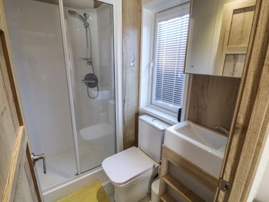 A bathroom with a shower cabin toilet sink and window with blinds at Gressingham 7 in Warton near Carnforth