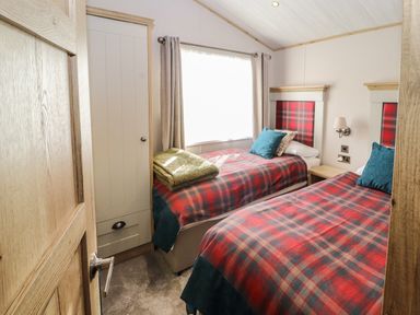 A bedroom with two single beds with red plaid bedding and blue pillows at Gressingham 7 in Warton near Carnforth