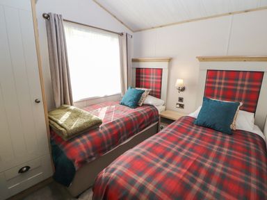 A bedroom with two single beds with red plaid bedding and blue pillows at Gressingham 7 in Warton near Carnforth