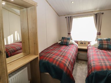 A bedroom with two single beds with plaid bedcovers and matching pillows at Gressingham 7 in Warton near Carnforth