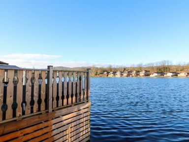A lake with wooden railing in the foreground and houses along the shore at Gressingham 7 in Warton near Carnforth