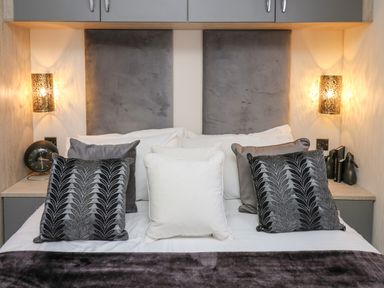 A bed with multiple pillows and wall lights on each side at 43 The Deri in Llanarth