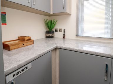 A kitchen corner with grey cabinets wooden trays a potted plant and window blinds at 43 The Deri in Llanarth