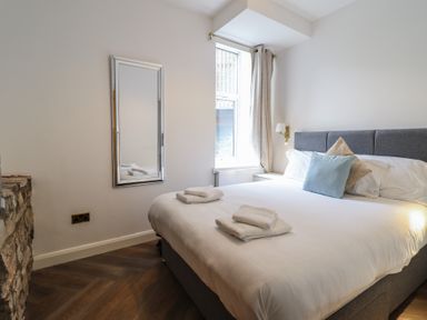 A bedroom with a bed and pillows and a window and a wall mirror at Gwydyr Bach 1 in Llanrwst