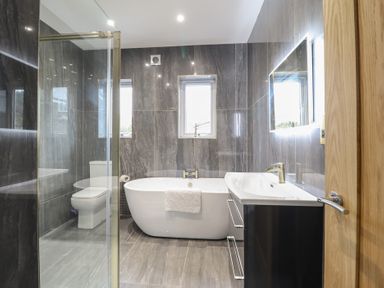 A bathroom with a bathtub toilet sink with cabinet and a shower enclosure at Gwydyr Bach 1 in Llanrwst