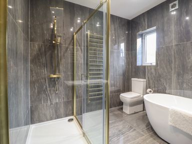 A bathroom with a shower enclosure a toilet a freestanding bathtub and a window at Gwydyr Bach 1 in Llanrwst