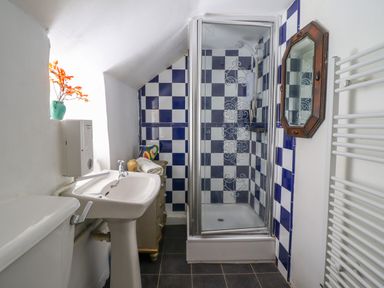 A bathroom with a white sink toilet and shower with blue and white tiles at Nyth Yr Eryr in Blaenau Ffestiniog