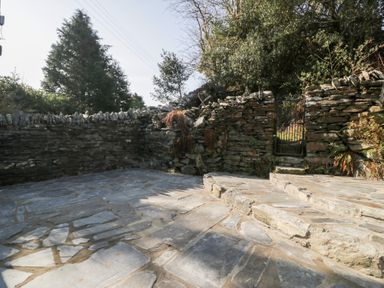 A stone patio with steps and a metal gate in a stone wall outdoors at Nyth Yr Eryr in Blaenau Ffestiniog