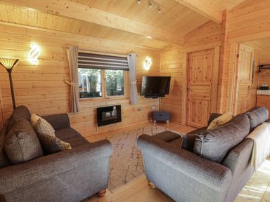 A living room with two gray sofas a wall mounted TV and a window at Little Lodge in Balminnoch near Glenluce