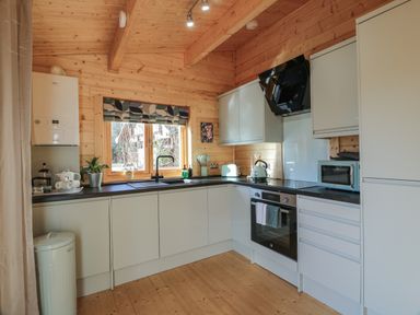 A kitchen with white cabinets black countertop wooden walls and ceiling at Little Lodge in Balminnoch near Glenluce