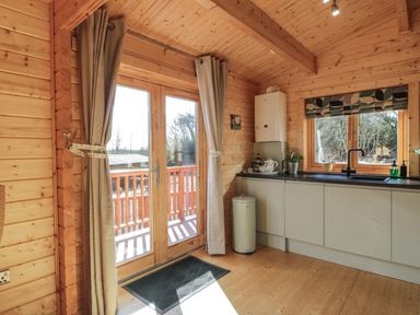 A kitchen with a sink counter a window and glass doors with curtains at Little Lodge in Balminnoch near Glenluce