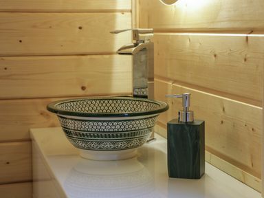 A patterned ceramic sink with a faucet and a soap dispenser on a countertop in a wooden bathroom at Little Lodge in Balminnoch near Glenluce