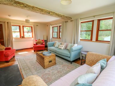 A living room with sofas and armchairs around a wooden coffee table at Oak Apple Cottage in Presteigne