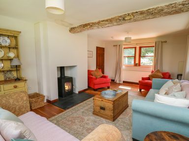 A living room with sofas a wooden chest coffee table and a wood burning stove at Oak Apple Cottage in Presteigne