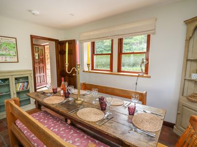 A dining room with a wooden table set with placemats glasses and cutlery at Oak Apple Cottage in Presteigne
