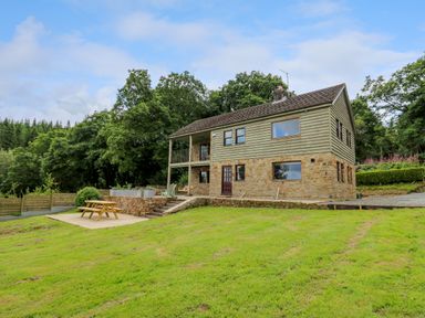 A house with stone and wood exterior surrounded by grass and trees at Oak Apple Cottage in Presteigne