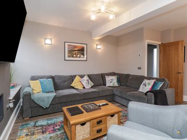 A living room with a gray sectional sofa and colorful pillows a wooden coffee table and a light blue armchair at Quarters Ambleside