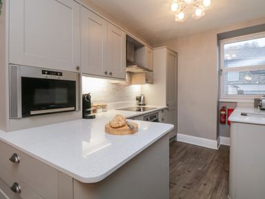 A kitchen with white countertops built in oven stove hood and cabinets at Quarters in Ambleside
