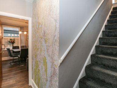 A stairway next to a hallway with a wall map and a dining room with a table and chairs at Quarters in Ambleside