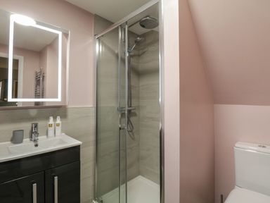 A bathroom with a shower enclosure a toilet and a sink with a mirror at Quarters in Ambleside