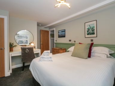 A bedroom with a bed pillows towels a desk with a round mirror and a chair at Quarters in Ambleside