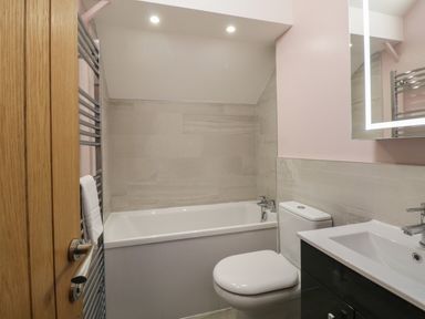 A bathroom with a bathtub toilet sink and a towel rail at Quarters in Ambleside
