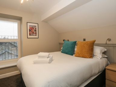 A bedroom with a double bed two pillows folded towels window and a bedside table at Quarters in Ambleside