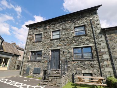 A stone building with windows a door and a picnic table outside at Quarters Ambleside
