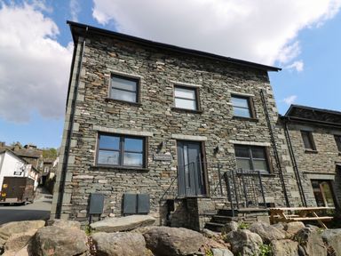 A stone building with multiple windows and a door with steps at Quarters in Ambleside