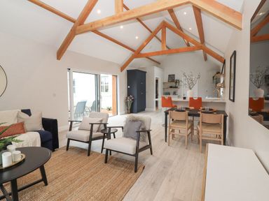 An open living and dining area with wooden beams a sofa two armchairs and a dining table with chairs at Curhoor Near Loughrea County Galway