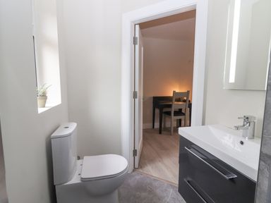 A bathroom with a toilet and sink leading to a room with a desk and chair at Curhoor Near Loughrea County Galway
