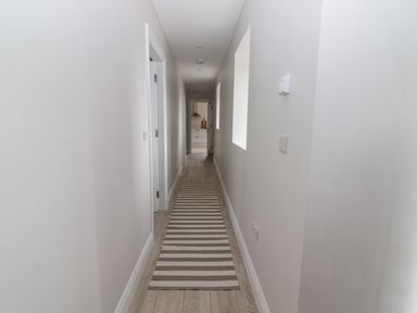 A long narrow hallway with a striped runner rug and light wooden flooring at Curhoor Near Loughrea County Galway