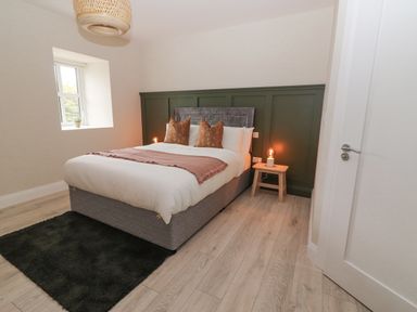 A bedroom with a double bed two pillows and bedside table with lamp near a window at Curhoor Near Loughrea County Galway