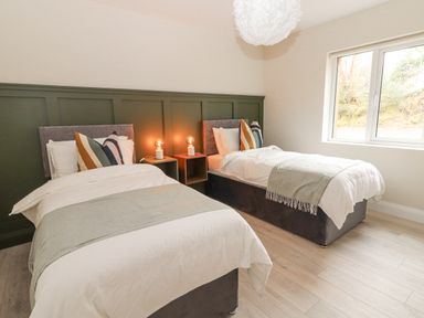 A bedroom with two single beds with pillows and blankets and two bedside tables with lamps near a window at Curhoor Near Loughrea County Galway