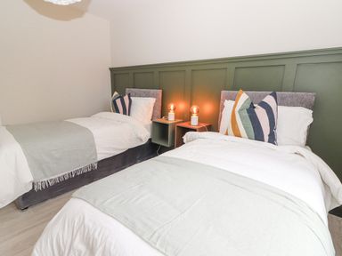 A bedroom with two beds white bedding striped pillows and two bedside tables with lamps at Curhoor Near Loughrea County Galway