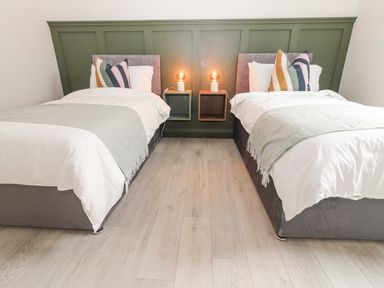 A bedroom with two single beds with white bedding and striped pillows with two lamps on wall-mounted bedside tables at Curhoor Near Loughrea County Galway