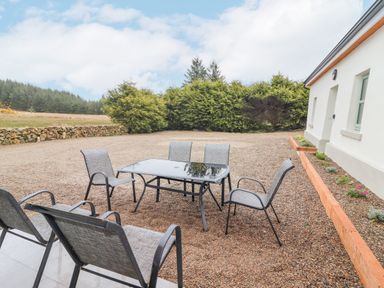 Outdoor patio area with glass table and six chairs beside a white building at Curhoor Near Loughrea County Galway