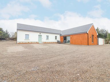 A single story house with white and wooden exterior walls and a gravel driveway at Curhoor Near Loughrea County Galway