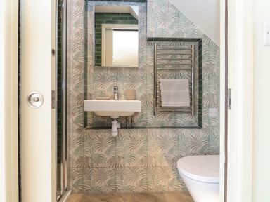 A small bathroom with a wall-mounted sink mirror towel rack and toilet at The Cabin at Ropewalk Goonbell near St Agnes