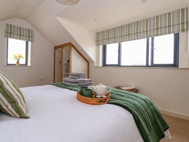 A bedroom with a bed covered with white and green bedding and a tray on the bed with a teapot and cups at The Cabin at Ropewalk Goonbell near St Agnes