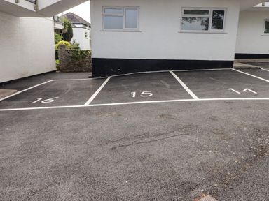 Three numbered parking spaces 14 15 and 16 adjacent to white buildings with windows at 14 Coedrath Park in Saundersfoot