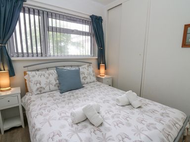 A bedroom with a bed covered in elephant patterned bedding and rolled towels at 14 Coedrath Park in Saundersfoot