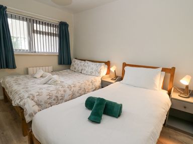 A bedroom with two beds side by side one with a patterned duvet and the other with a plain white duvet at 14 Coedrath Park in Saundersfoot